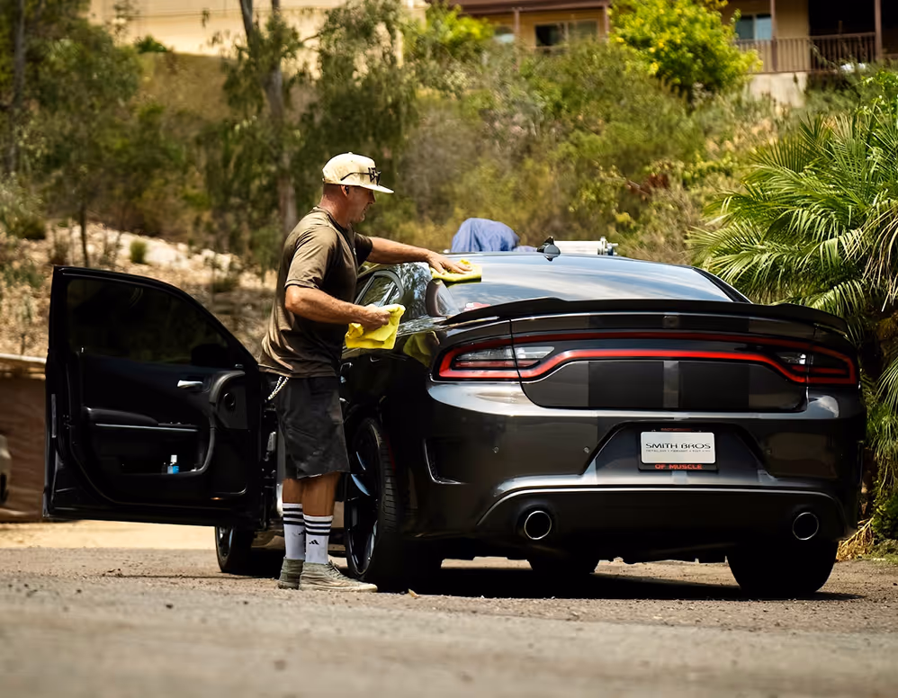 Detailer wiping down a Dodge Charger with dark tinted windows