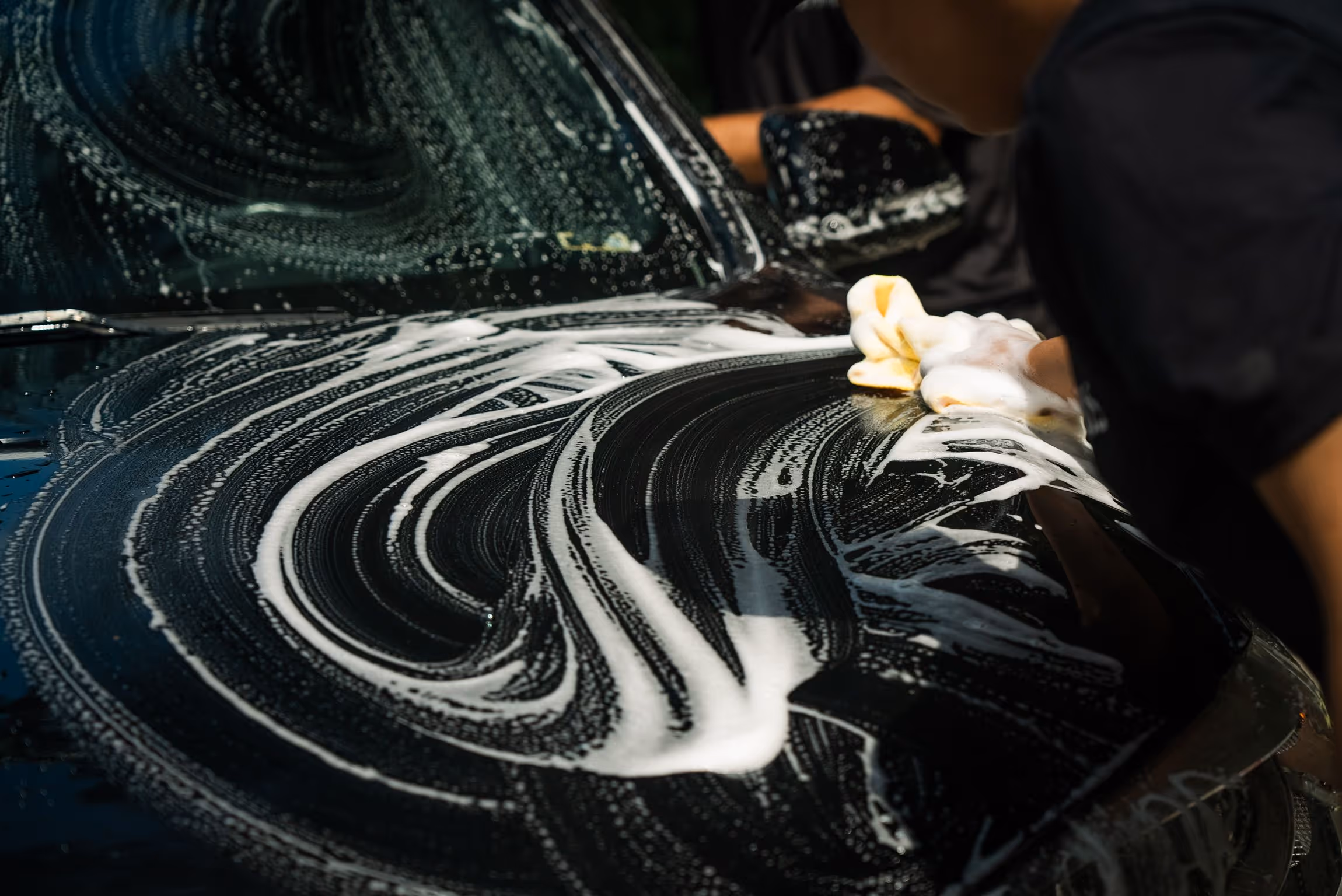 Car being hand washed with soap and a wash mitt